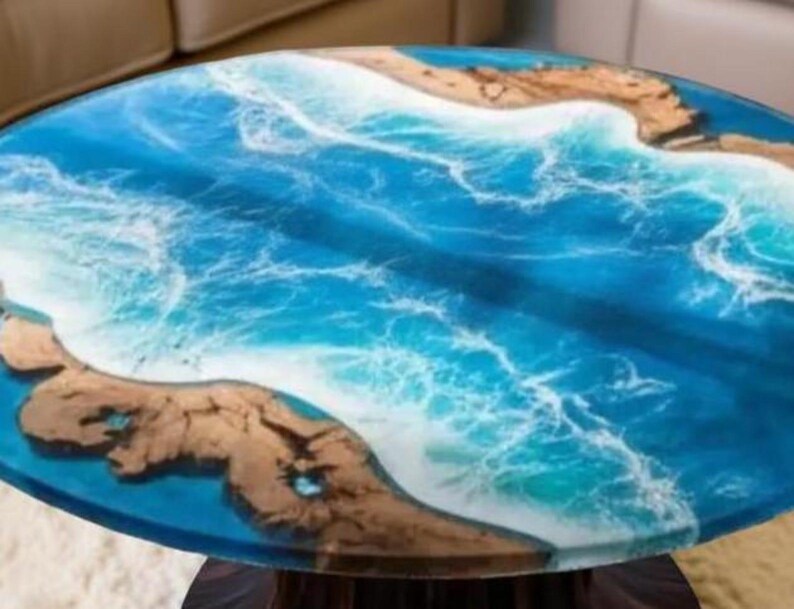 May include: Oval coffee table with a resin top depicting an ocean scene. The table features shades of blue and white resin, with sections of brown wood resembling landmasses. The table is supported by a dark wooden base.