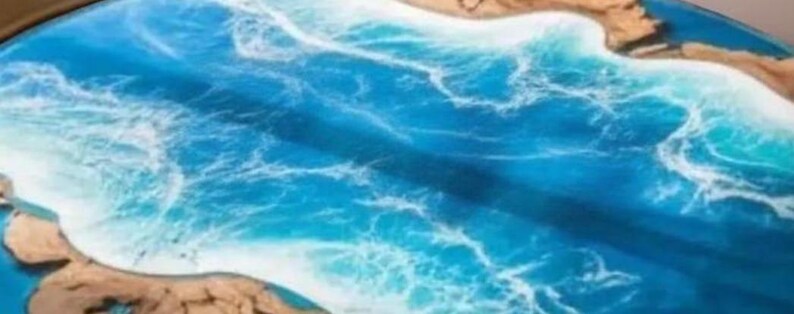 May include: A handcrafted epoxy resin table with a vibrant ocean design. The table features shades of blue and white, mimicking waves and sea foam. The edges are a natural wood color, creating a coastal theme. The table's surface is smooth and glossy.
