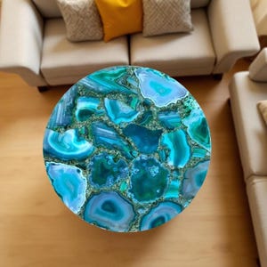 May include: A round coffee table with a mosaic top made of blue and green agate stone. The table's surface is a vibrant mix of colors and patterns, creating a unique and eye-catching design. The table is a decorative piece for a living room.