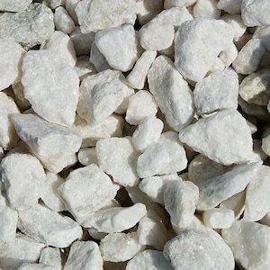 May include: Close-up of a pile of white decorative rocks. The rocks vary in size and shape, with a rough, textured surface. The color is a bright, clean white, and the rocks are tightly packed together.
