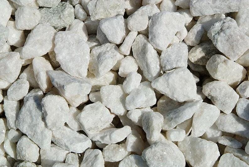 May include: Close-up of a pile of white decorative rocks. The rocks vary in size and shape, with a rough, textured surface. The color is a bright, clean white, and the rocks are tightly packed together.