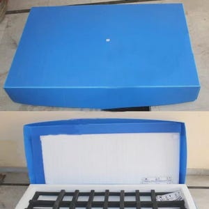May include: A blue packing box, open to reveal a white interior with a black grid structure. The box is rectangular with a matching blue lid. The text "PACKING BOX" is at the top.