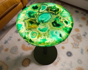 May include: A round side table with a vibrant green and yellow agate top. The table has a black, circular base and a single black stem. The table's top is approximately 18 inches in diameter.