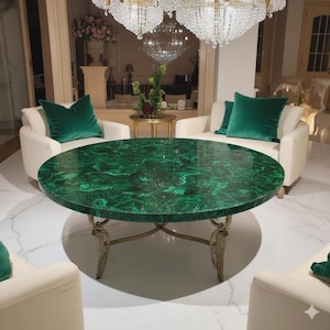 Può includere: Un tavolo rotondo in malachite verde con superficie lucida. Il tavolo ha una base dorata e ornata ed è circondato da poltrone bianche con cuscini di velluto verde. La stanza presenta un lampadario e pavimenti in marmo.