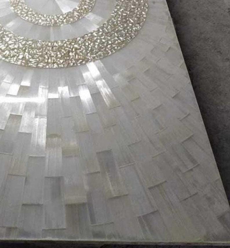 Puede incluir: Primer plano de un dise&ntilde;o de mosaico rectangular blanco. El mosaico presenta un patr&oacute;n circular en la parte superior con un borde texturizado de color plateado. El resto del azulejo est&aacute; formado por piezas rectangulares.