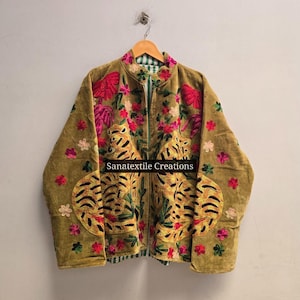 Könnte beinhalten: Eine senfgelbe Jacke mit aufwendigen Stickereien von zwei Tigern sowie rosa und roten Blumen. Das Kleidungsstück hat einen Stehkragen, lange Ärmel und einen Reißverschluss auf der Vorderseite. Der Text Sanatextile Creations ist zu sehen.