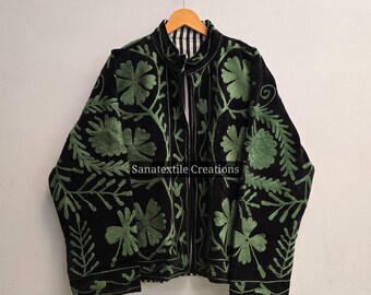 May include: Black jacket with green floral embroidery. The jacket has a full zipper and a stand-up collar. The embroidery features a detailed floral pattern. The text "Sanatextile Creations" is visible on the jacket.