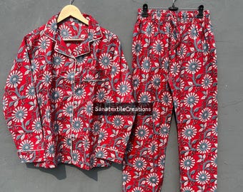 May include: Red pajama set with a floral pattern. The set includes a button-down shirt and matching pants. The floral design features blue and white flowers on a red background. The shirt has a white trim.