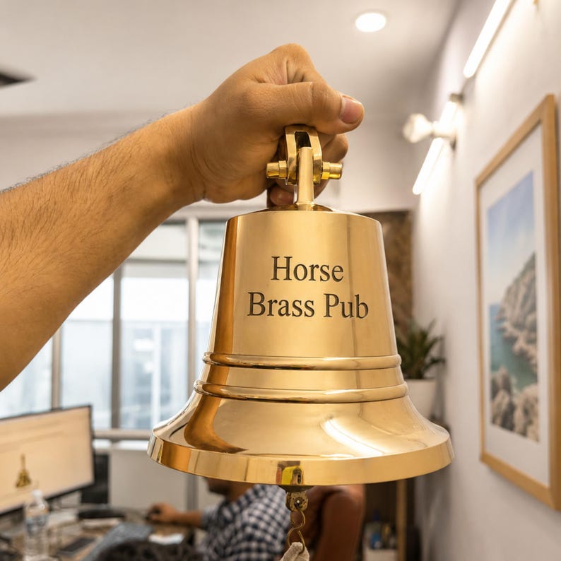 Pode incluir: Um sino de lat&atilde;o polido com borda alargada e suporte de montagem no topo. O texto "Horse Brass Pub" est&aacute; gravado em uma fonte serifada escura na frente do sino. Um pequeno la&ccedil;o de metal est&aacute; preso na parte inferior para o badalo.