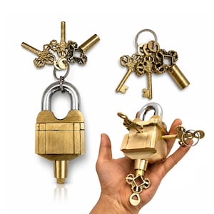 May include: A selection of brass padlocks and keys. The padlocks feature a silver shackle and are accompanied by ornate, vintage-style keys. One padlock is shown being held in a hand. The keys have decorative designs.