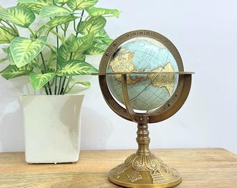 Globo armilar de latón con grabados celestes y base floral – Pieza astronómica decorativa giratoria.