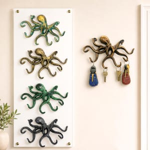 May include: Octopus-shaped wall hooks in bronze, green, and black. The octopus hooks are mounted on a white board and also individually. One octopus hook holds keys. The design adds a nautical theme to any room.