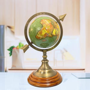 May include: A vintage-style globe with a green and yellow map, set within a bronze-colored meridian ring. The globe sits on a wooden base with a brass-colored stand. Two arrow-shaped pointers are attached to the meridian ring, adding to its antique aesthetic.