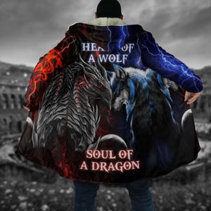 Könnte beinhalten: Schwarzer Kapuzenmantel mit Drachen- und Wolfsmotiv und dem Text "HEAD OF A WOLF" und "SOUL OF A DRAGON". Der Umhang hat rote und blaue Blitzmuster und ein weißes Sherpa-Futter.
