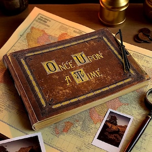 May include: A vintage-style journal with the words "ONCE UPON A TIME" in gold lettering on the cover. The journal is brown with a worn texture, suggesting an antique aesthetic. It rests on a map, with a magnifying glass and photos nearby.