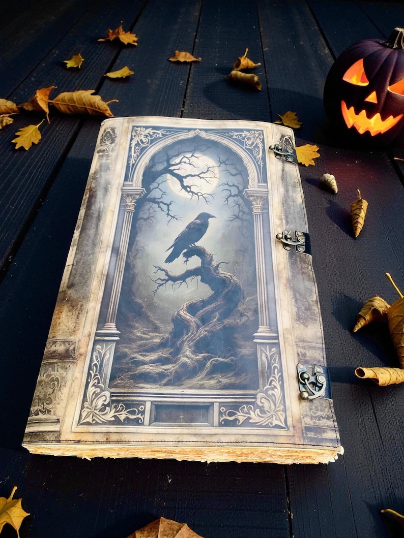 Op de afbeelding: Een groot boek in antieke stijl met een gedetailleerde illustratie van een raaf die op een tak zit onder een volle maan. De kaft heeft sierlijke metalen sluitingen en decoratieve randen. De sc&egrave;ne roept een gotisch of Halloween-thema op.