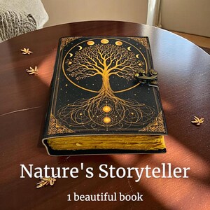 May include: A black journal with a gold tree of life design and the text "Nature's Storyteller". The journal has a clasp closure and gold-colored edges. The book is on a dark brown wooden table.