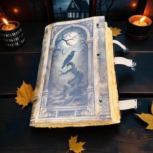Op de afbeelding: Een open boek in antieke stijl met een gedetailleerde illustratie van een raaf die op een tak zit onder een volle maan. Het boek heeft verouderde, vergeelde pagina's en decoratieve sluitingen. Herfstbladeren en brandende kaarsen omringen het boek en cre&euml;ren een gotisch thema.