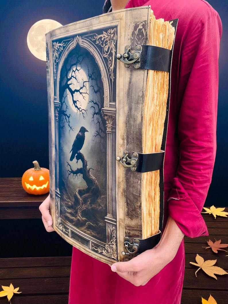 Op de afbeelding: Een groot boek in antieke stijl met een illustratie van een raaf op de omslag. De omslag toont een volle maan, kale bomen en een gotisch boogontwerp. Het boek is gebonden met zwarte leren banden en metalen sluitingen. De pagina's hebben een vintage uitstraling.