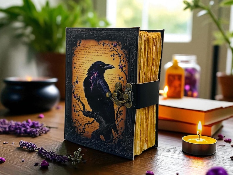 May include: A leather-bound journal with a raven illustration. The cover features a black raven perched on a branch against a parchment-like background. The journal is secured with a black leather strap and a decorative clasp. The pages have a yellowed, aged appearance.