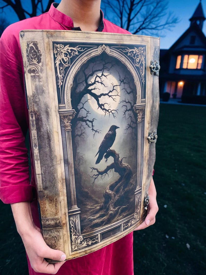 Op de afbeelding: Een groot, decoratief boek met een gotische illustratie van een raaf op een tak onder een volle maan. Het boek heeft sierlijke goudkleurige metalen sluitingen en een gedetailleerde, verouderde uitstraling, wat wijst op een vintage- of fantasiethema.