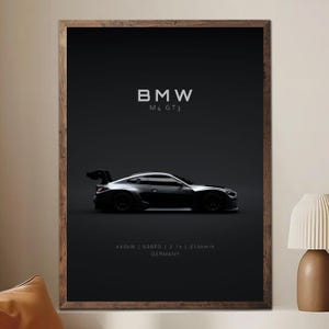 May include: Framed print featuring a black BMW M4 GT3 race car. The poster includes the car's specifications: 440kW, 598PS, 3.1s, and 310km/h, with "GERMANY" at the bottom. The car is set against a dark background.
