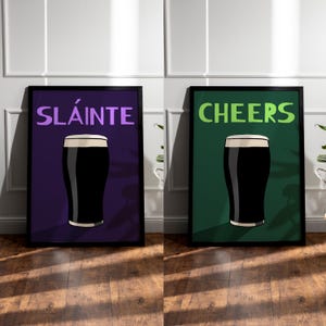 May include: Two framed art prints. One features the word "SL&Aacute;INTE" in purple above a pint of stout on a purple background. The other print says "CHEERS" in green above a pint of stout on a green background.