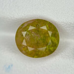 May include: Oval-shaped, yellow-green gemstone with a starburst design. The gem is translucent, with internal inclusions visible. The colour varies from pale yellow to a deeper olive green, giving it a unique look. Suitable for jewellery making.