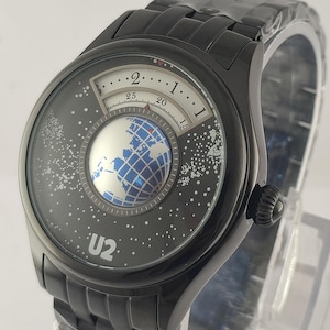 May include: Black wristwatch with a unique face design. The watch face features a globe graphic and a starry background, with the text "U2" visible. The watch has a black metal band and a black bezel.