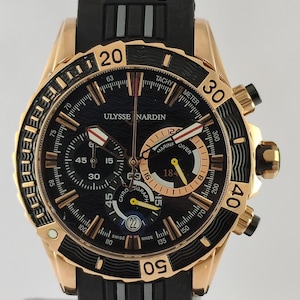 May include: A rose gold and black Ulysse Nardin Marine Diver chronograph watch with a black rubber strap. The black dial features a wave pattern, luminous hands, three sub-dials, a date window at the six o'clock position, and tachymeter markings.