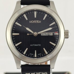May include: A Roamer automatic wristwatch with a black dial and silver hands. The watch has a stainless steel case and a black leather strap with white stitching. The day and date are displayed at the 3 o'clock position. The watch is Swiss made.