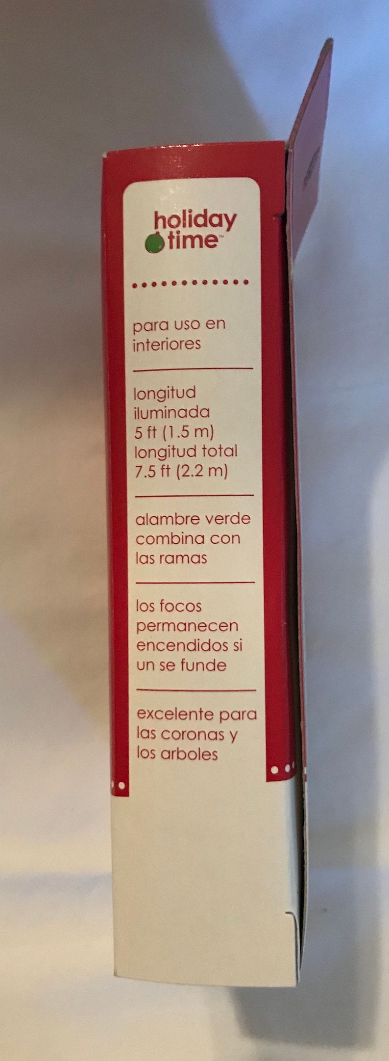 May include: A red and white box with the text "holiday time" and information about a string of lights. The lights are 5 feet long and have a total length of 7.5 feet. The lights are green and can be used indoors. The text also says that the lights are excellent for wreaths and trees.