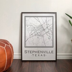 Könnte beinhalten: Ein Schwarz-Weiß-Karten-Druck von Stephenville, Texas in einem schwarzen Rahmen. Die Karte ist auf weißem Hintergrund mit schwarzen Linien und Text. Der Druck befindet sich auf einem Holzboden mit einem braunen Ledersessel und einer Topfpflanze in einem geflochtenen Korb.