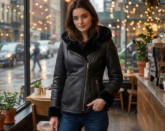 May include: A black leather jacket with a hood, featuring a soft black faux fur lining, a diagonal gold-tone zipper closure, and two zippered side pockets. The jacket has long sleeves with black faux fur cuffs and is paired with blue denim jeans.