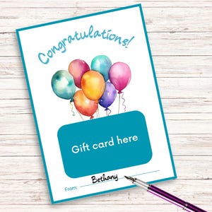 Peut inclure: Une carte cadeau blanche avec une bordure turquoise et une illustration à l'aquarelle de ballons colorés. La carte indique "Félicitations !" et "Carte cadeau ici". Un stylo repose sur la carte, avec le nom "Bethany" écrit dessus.