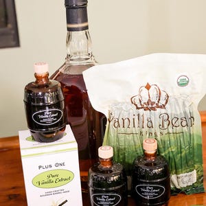 May include: A collection of vanilla products, including bottles of pure vanilla extract and a bag of vanilla beans. The extract bottles have a dark label and a wooden cap. A box of vanilla extract is also present.