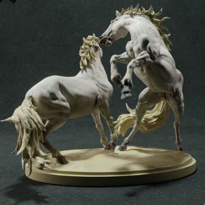 Puede incluir: Una escultura que presenta dos caballos blancos sobre una base circular de color canela. Un caballo se alza sobre sus patas traseras con la boca abierta, mientras que el otro est&aacute; de pie sobre sus cuatro patas frente a &eacute;l. Ambos tienen crines y colas detalladas.
