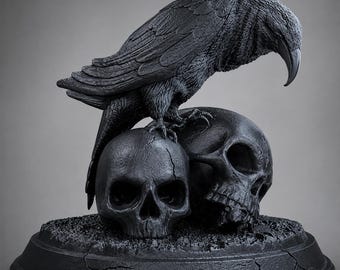 Puede incluir: Una escultura de color negro mate que presenta un cuervo detallado posado sobre dos cráneos humanos. El ave tiene plumas texturizadas y un pico curvado, mientras que los cráneos muestran estructuras óseas realistas con grietas. La pieza descansa sobre una base circular.
