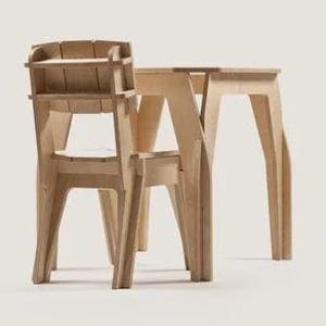 Puede incluir: Un juego de silla y mesa de madera clara. La silla tiene respaldo de listones y reposabrazos, mientras que la mesa tiene una tapa rectangular simple. Ambas piezas tienen un diseño moderno y geométrico y están hechas de madera sin terminar.
