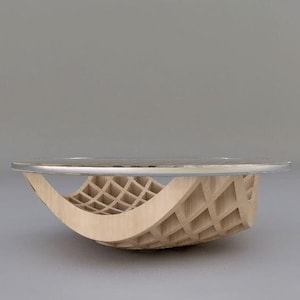 Puede incluir: Una mesa de centro moderna con una tapa de cristal transparente y una base de madera curvada con diseño de celosía. La base es de madera clara y tiene un diseño arquitectónico único. Adecuada para salones y otros espacios.