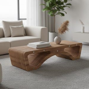 May include: A contemporary wooden coffee table with a distinctive slatted design. The table is light brown and has an arched base. Books and a vase with decorative elements sit on top. The table is in a living room setting.