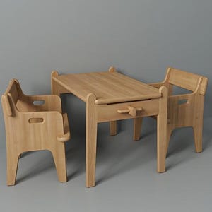 May include: A light-colored wooden children's table and chair set. The table has a small drawer with a wooden handle. The chairs have armrests and cut-out details. The set is made of light-colored wood.