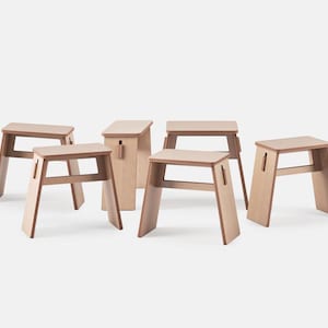May include: A set of light-coloured wooden stools and a matching storage box. The stools feature a simple, modern design with angled legs and a rectangular seat. The storage box has a lid and a handle. The furniture is made of light-coloured wood.
