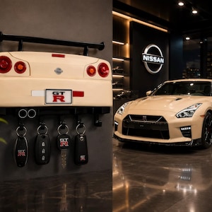Op de afbeelding: Een wandhouder voor sleutels in de vorm van de achterkant van een beige Nissan GT-R, voorzien van een zwarte spoiler, ronde rode achterlichten en een GT-R kentekenplaat. Vier zwarte haken houden diverse autosleutels met GT-R-logo.