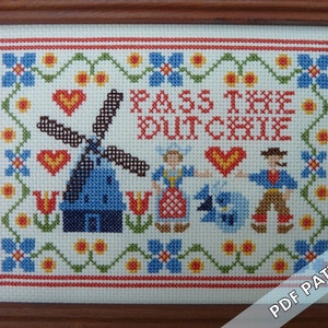 May include: Cross-stitch pattern featuring a windmill, tulips, and two people in traditional Dutch clothing. The text "Pass the Dutchie" is stitched in red and white.