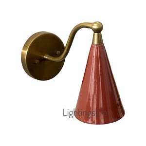 May include: A wall-mounted light fixture with a conical, reddish-brown shade. The fixture has a brass-colored arm and a circular base. The text "Lightings" is visible on the bottom right. This decorative lamp is suitable for interior lighting.