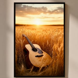 May include: Acoustic guitar leaning against wheat stalks in a field, framed in a black border. The guitar has a light wood finish and a dark sound hole. The background features a sunset with a golden glow.
