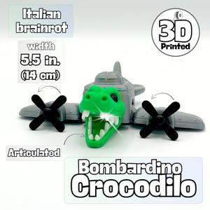May include: A 3D-printed toy airplane with a green crocodile head and black propellers. The toy is gray with a green articulated crocodile head. The width is 14 cm. The text "Bombardino Crocodilo" is visible.