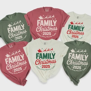 May include: Six short-sleeved crew neck t-shirts in red, olive green, and cream colors. Each shirt features a graphic print of a Santa sleigh with reindeer, the text "FAMILY Christmas 2025", and the phrase "Making Merry Memories Together".