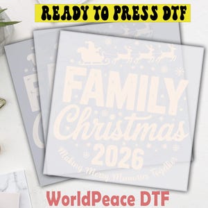 May include: A square DTF transfer sheet featuring a light-colored graphic with a Santa sleigh and reindeer silhouette, the text FAMILY Christmas 2026, and the phrase Making Merry Memories Together, accented by small snowflake icons throughout.